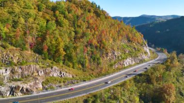 Aerial view of highway road in North Carolina through Appalachian mountains in golden fall season with fast moving trucks and cars. Interstate transportation concept.