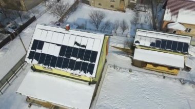 Aerial view of snow melting from covered solar photovoltaic panels installed on house rooftop for producing clean electrical energy. Low effectivity of renewable electricity in nothern region winter.