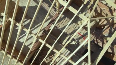 Aerial view of unfinished residential house with wooden roof frame structure under construction.