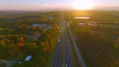 Elevated view of freeway road lanes with fast moving traffic cars and trucks in North Carolina golden fall season at sunrise. Interstate transportation infrastructure in USA.