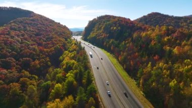 I-40 freeway in North Carolina leading to Asheville through Appalachian mountains in golden fall with fast moving trucks and cars. Interstate transportation concept.