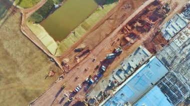 Aerial view of construction site with assembly of modern large factory structure for production and distribution of industrial products. Concept of global industry development.