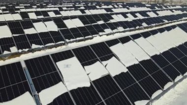 Aerial view of electrical power plant with solar panels covered with snow melting down in winter end for producing clean energy. Concept of low effectivity of renewable electricity in northern region.