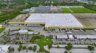 Aerial view of large commercial distribution center with many trucks unloading and uploading retail products for further shipment.