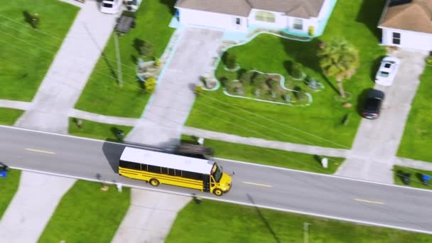 早朝に子供たちのための彼らのレッスンを拾うために郊外の通りに運転するアメリカの黄色のスクールバスの空中ビュー アメリカの公共交通機関 — ストック動画