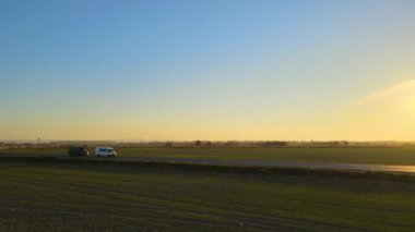 Gün batımında hızlı giden arabalarla şehirlerarası yol manzarası. Akşamları otoban trafiğinin insansız hava aracı görüntüsü.