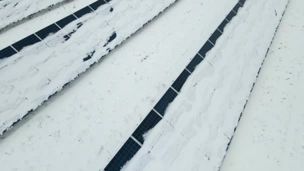 雪の空中ビューは クリーン電気エネルギーを生産するための太陽光発電パネルの多くの行で持続可能な発電所をカバーしました 冬の再生可能エネルギーの有効性が低い — ストック動画