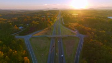 Elevated view of freeway exit junction over road lanes with fast moving traffic cars and trucks in North Carolina golden fall season at sunset. Interstate transportation infrastructure in USA.