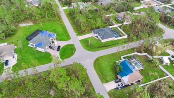 ハリケーンイアンはアスファルトの帯状疱疹の交換まで雨の水漏れに対する保護プラスチック製のタープで覆われた家の屋根を損傷した 自然災害の余波 — ストック動画