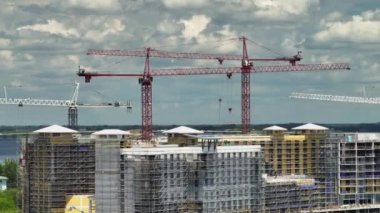 Tower cranes and frame structure of high residential apartment buildings at construction site. Real estate development.