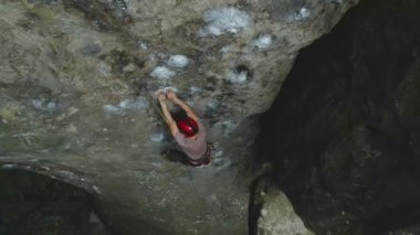 Genç adam dik kayalık dağ duvarına tırmanıyor. Erkek tırmanışçı zorlu rotayı aşar. Ekstrem spor konseptine dalmak.