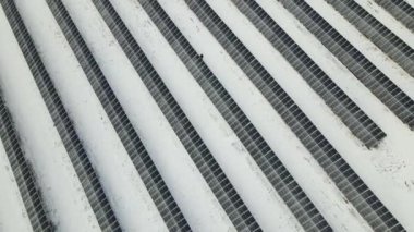 Aerial view of electrical power plant with solar panels covered with snow melting down in winter end for producing clean energy. Concept of low effectivity of renewable electricity in northern region.