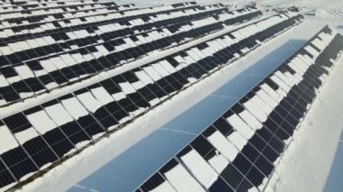 Aerial view of snow melting from covered solar photovoltaic panels at sustainable electric power plant for producing clean electrical energy. Low effectivity of renewable electricity in winter.