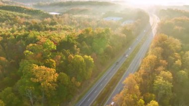 Sonbahar ormanları arasında hızla ilerleyen yoğun Amerikan otobanının manzarası. Eyaletler arası ulaşım kavramı.