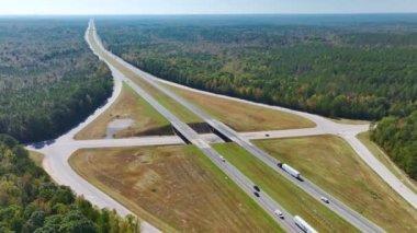 View from above of busy american highway with fast moving traffic between woods. Interstate transportation concept.