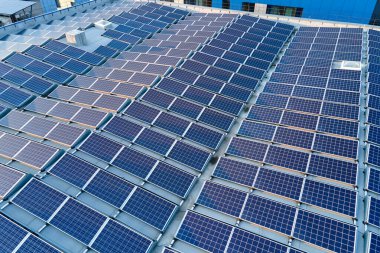 Sanayi binasının çatısına yeşil ekolojik elektrik üretmek için monte edilen mavi fotovoltaik güneş panellerinin hava görüntüsü. Sürdürülebilir enerji konsepti üretimi.