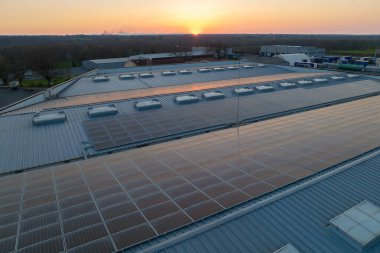 Sanayi binasının çatısına yeşil ekolojik elektrik üretmek için monte edilmiş mavi fotovoltaik panelli güneş enerjisi santralinin hava görüntüsü. Sürdürülebilir enerji konsepti üretimi.