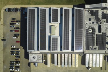Sanayi binasının çatısına yeşil ekolojik elektrik üretmek için monte edilmiş mavi fotovoltaik panelli güneş enerjisi santralinin hava görüntüsü. Sürdürülebilir enerji konsepti üretimi.