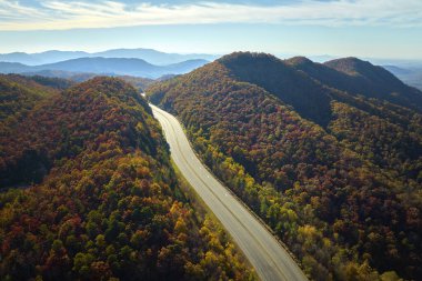 Empty free of vehicles I-40 freeway road leading to Asheville in North Carolina thru Appalachian mountains with yellow fall forest. High gas prices and energy crisis concept.