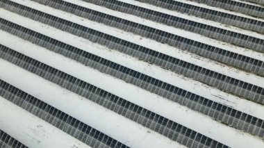 Aerial view of snow melting from covered solar photovoltaic panels at sustainable electric power plant for producing clean electrical energy. Low effectivity of renewable electricity in winter.