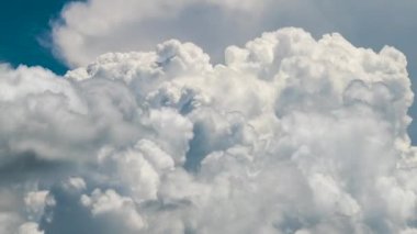 Beyaz kabarık kümülüs bulutlarının zamanı yaz mavi gökyüzünde şekilleniyor. Hareket eden ve değişen bulutlu hava durumu.