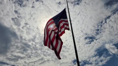 ABD ulusal bayrağı mavi gökyüzüne karşı rüzgarda dalgalanıyor. Amerikan yıldızları ve çizgileri demokrasinin sembolü olarak gösterildi..