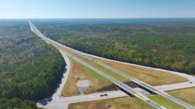 View from above of busy american highway with fast moving traffic between woods. Interstate transportation concept.