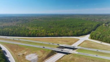 Aerial view of freeway overpass junction with fast moving traffic cars and trucks in american rural area. Interstate transportation infrastructure in USA.