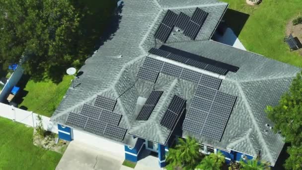 きれいな生態系の電気エネルギーを生成するための青い太陽光発電パネルと普通のアメリカの家庭の屋根の空中ビュー 排出ゼロをコンセプトとした再生可能エネルギー — ストック動画