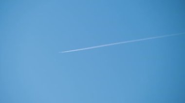 Mesafeli yolcu jet uçağı açık mavi gökyüzünde yüksek irtifada uçarken ardında beyaz duman izi bırakıyor. Hava taşımacılığı kavramı.