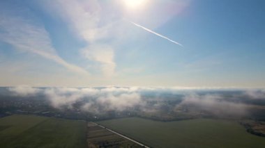 Aerial view from high altitude of landscape covered with puffy morning fog. Cold humid air condensing in rain clouds.