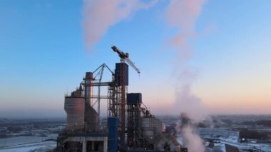 Yüksek beton fabrika yapısı ve sanayi bölgesinde kule vinçleri olan çimento fabrikasının hava görüntüsü. Sera gazı havayı kirletiyor. Üretim ve küresel sanayi kavramı.