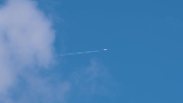 Uzaktaki Yolcu Uçağı Mavi Gökyüzünde Yüksek Irtifada Uçarken Beyaz Bulutlar — Stok video