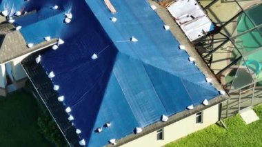 Ian Kasırgası, asfalt kiremitleri değişene kadar yağmur suyuna karşı koruyucu plastik muşambayla kaplı evin çatısına zarar verdi. Doğal afetten sonra.