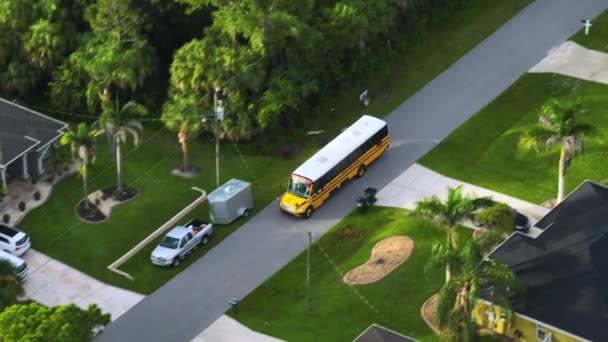 早朝に子供たちを迎えに田舎町の通りを走る古典的なアメリカの黄色のスクールバスのトップビュー アメリカの公共交通機関 — ストック動画