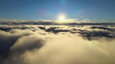 Yükseklerden gökyüzü manzarası. Akşamları yoğun, kabarık kümülüs bulutları uçuşuyor. Uçak penceresinden gün batımı inanılmaz..