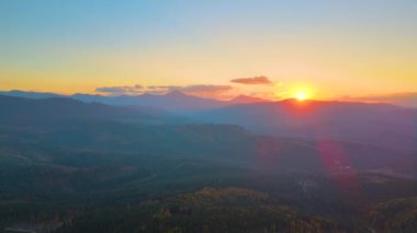 Güzel bir akşam panoramik manzarası. Gün batımında uzak dağ tepeleri üzerinde parlak batan güneş..