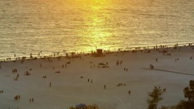 Sarasota, ABD 'de yumuşak beyaz kumlu ünlü Siesta Key plajı. Birçok insan sıcak körfez sularında yıkanarak ve gün batımında sıcak Florida güneşi altında bronzlaşarak tatil yapıyor..