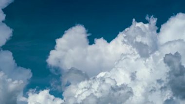 Yazın mavi gökyüzünde fırtınadan önce beyaz tüylü kümülonimbus bulutları oluşuyor. Hareket eden ve değişen bulutlu hava durumu.