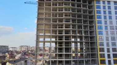 Vinç kaldırma kulesi ve inşaat halindeki monolitik çerçeveli yüksek konutlu bina. Gayrimenkul geliştirme.