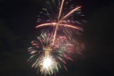 Aerial view of bright fireworks exploding with colorful lights against dark night sky on US Independence day holiday.