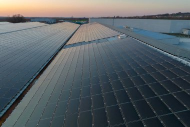 Sanayi binasının çatısına yeşil ekolojik elektrik üretmek için monte edilmiş mavi fotovoltaik panelli güneş enerjisi santralinin hava görüntüsü. Sürdürülebilir enerji konsepti üretimi.