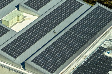 Sanayi binasının çatısına yeşil ekolojik elektrik üretmek için monte edilmiş mavi fotovoltaik panelli güneş enerjisi santralinin hava görüntüsü. Sürdürülebilir enerji konsepti üretimi.