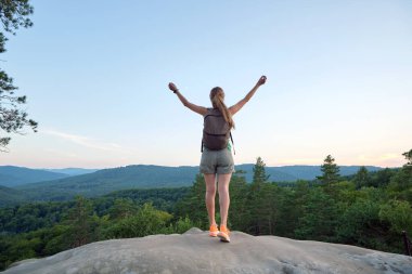 Genç kadın yürüyüşçü, elleri dağlık patikada tek başına duruyor ve vahşi doğa manzarasının tadını çıkarıyor. Aktif yaşam konsepti.