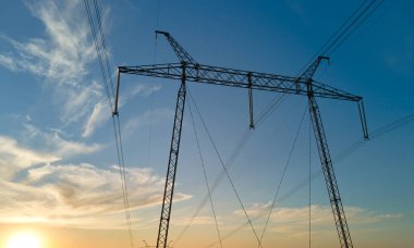 Gün batımında elektrik hatları olan yüksek voltaj kulesi. Elektrik aktarımı.
