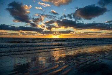 Yumuşak akşam deniz dalgalarının kumlu sahilde ezdiği okyanus batımı manzarası..