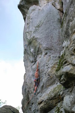 Güçlü erkek tırmanıcı kayalık dağın dik duvarına tırmanıyor. Sporcu zor yolu aştı. Ekstrem spor hobisi konsepti.