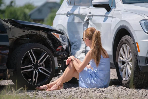 Stressed woman driver sitting on street side shocked after car accident. Road safety and insurance concept.