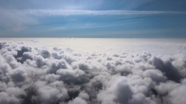 Dünya 'nın yüksek irtifasındaki uçak penceresinden hava manzarası beyaz kabarık kümülüs bulutlarıyla kaplı..
