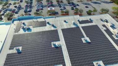Aerial view of blue photovoltaic solar panels mounted on shopping mall building roof for producing green ecological electricity. Production of sustainable energy concept.